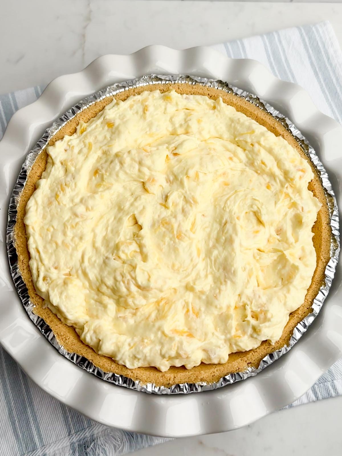 no bake pineapple cream cheese pie in a white pie plate