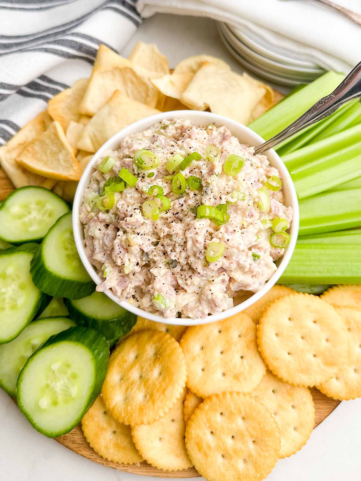 old fashioned ham salad in a white bowl surrounded by cucumbers, celery, and crackers