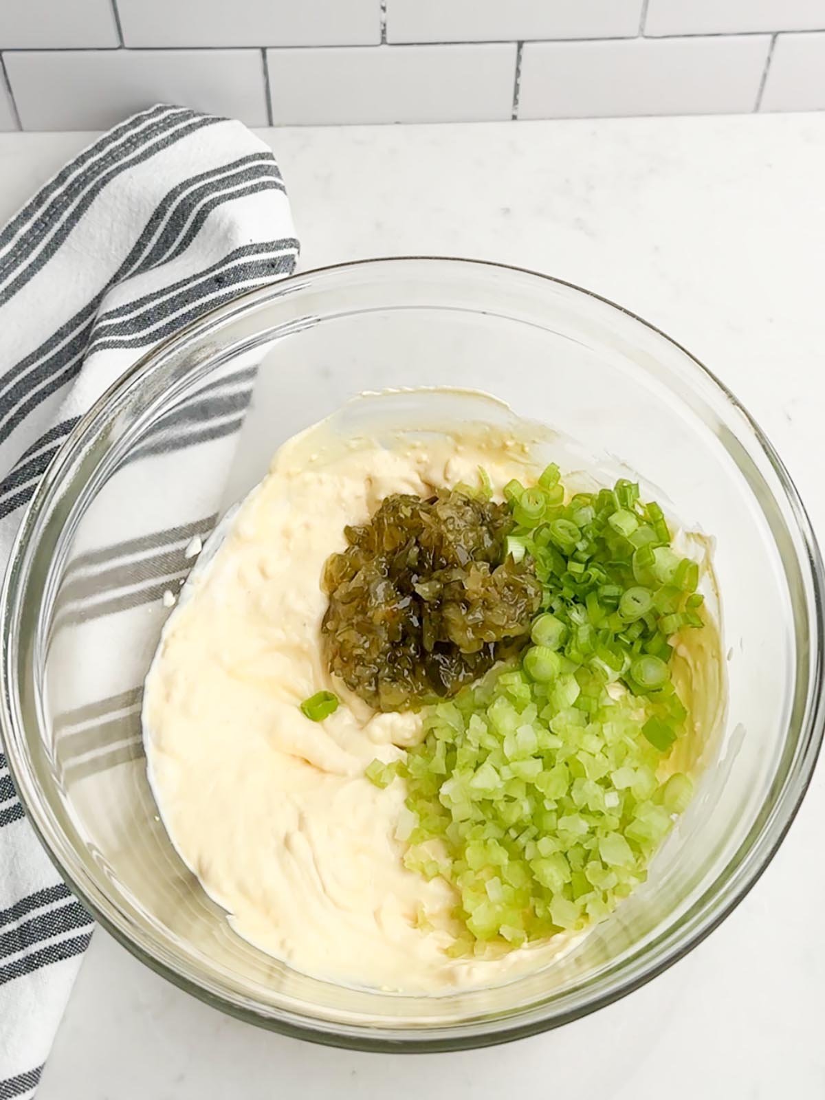 mayo mixture, relish, green onions, and celery in a clear bowl