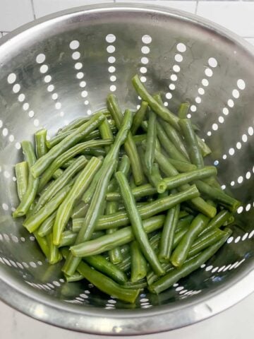 cooked green beans in a colander.