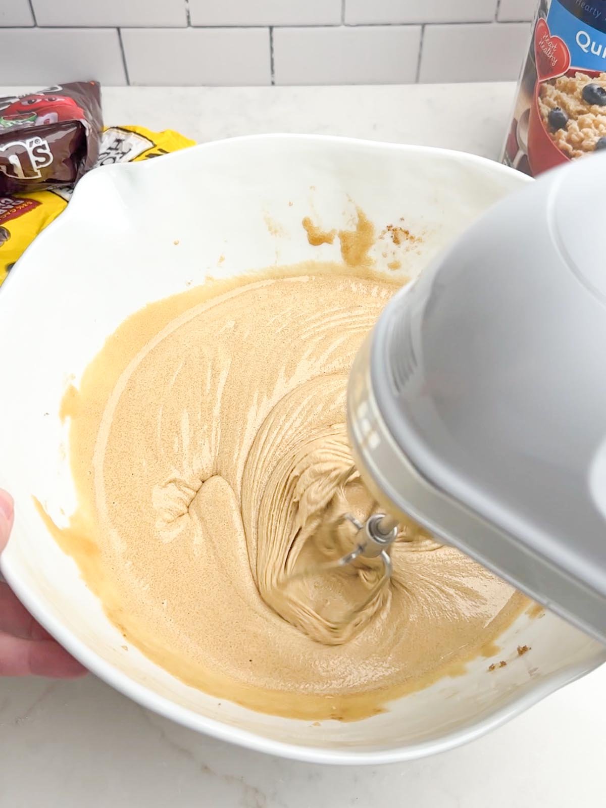 Mixer combining eggs and sugars in a white mixing bowl.