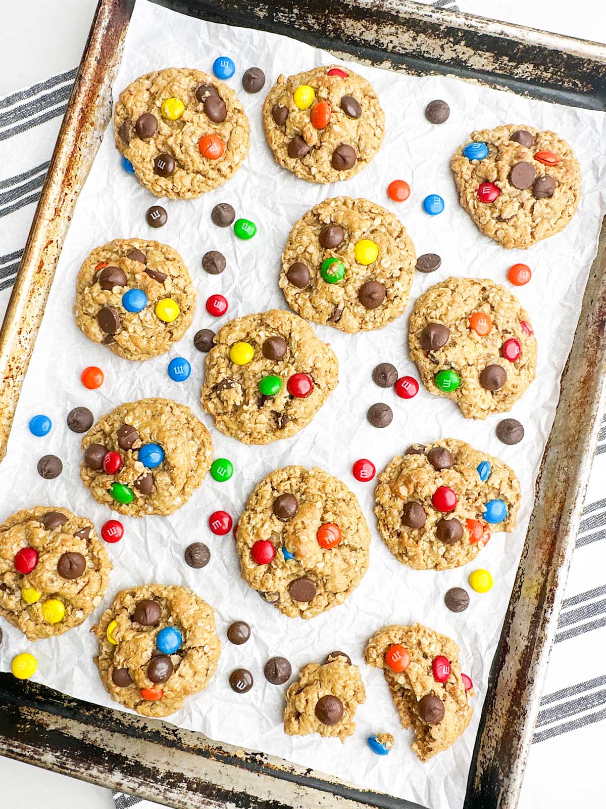 Monster cookies on parchment paper on a baking pan.