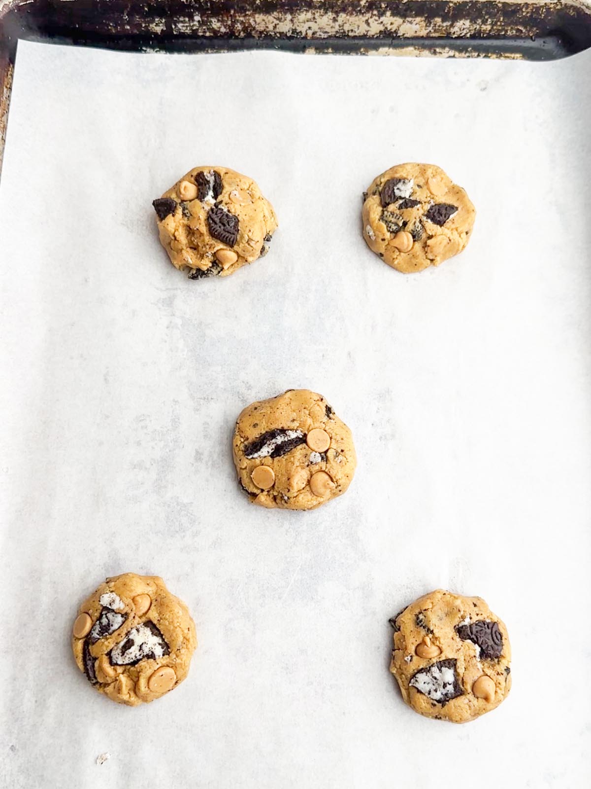 Peanut butter Oreo cookie dough balls on baking sheet.