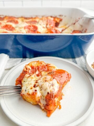 pizza casserole on a white plate in front of a casserole dish.