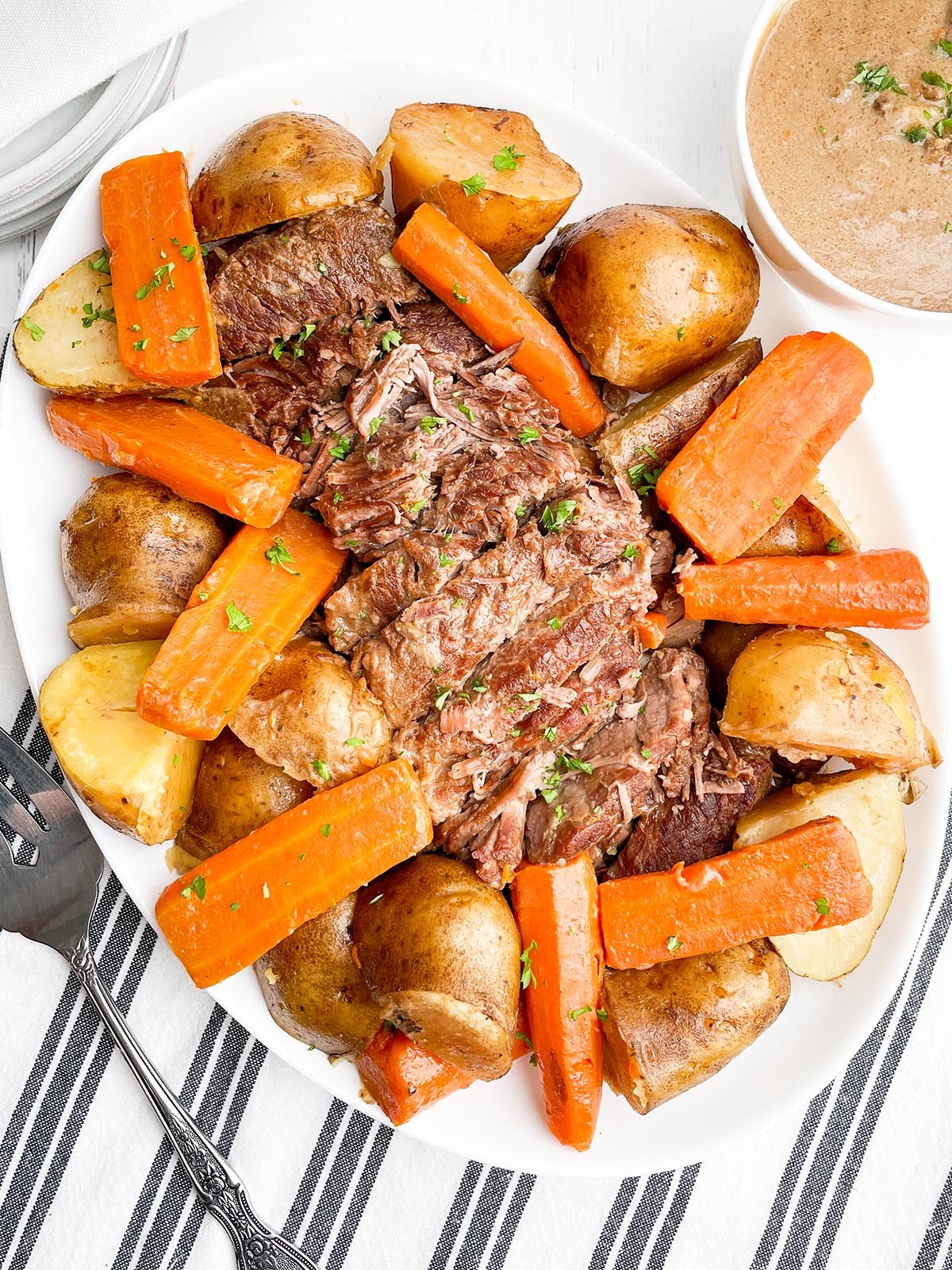 Pot roast with onion soup mix, potatoes, and carrots on a white platter.