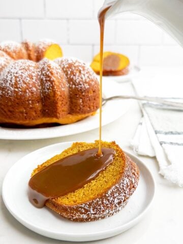 pumpkin cake with yellow cake mix on a white plate with caramel sauce being drizzled on top.