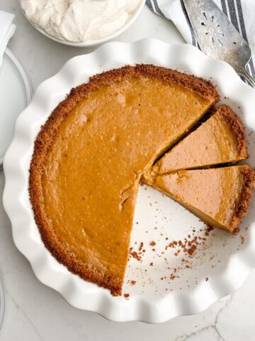 pumpkin pie with graham cracker crust in white pie plate.