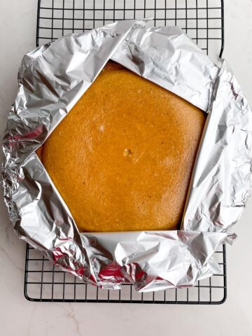 pieces of foil covering the edges of the graham cracker crust.