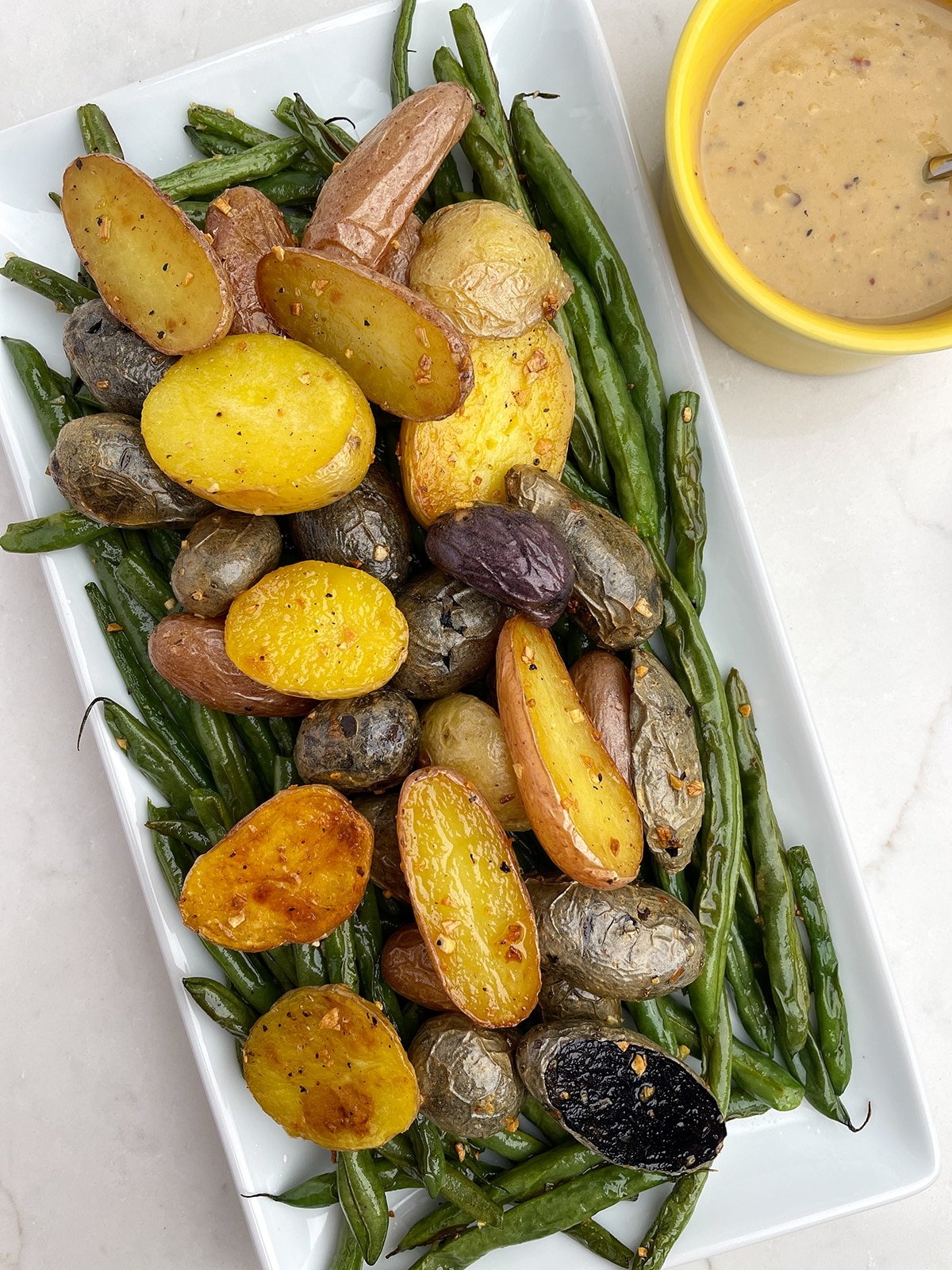 Roasted Potatoes and Green Beans on a white platter on white countertop