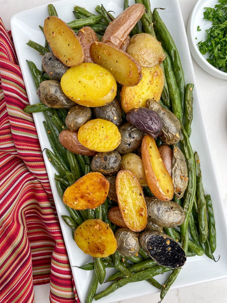 Roasted Potatoes and Green Beans on a white platter with a red napkin