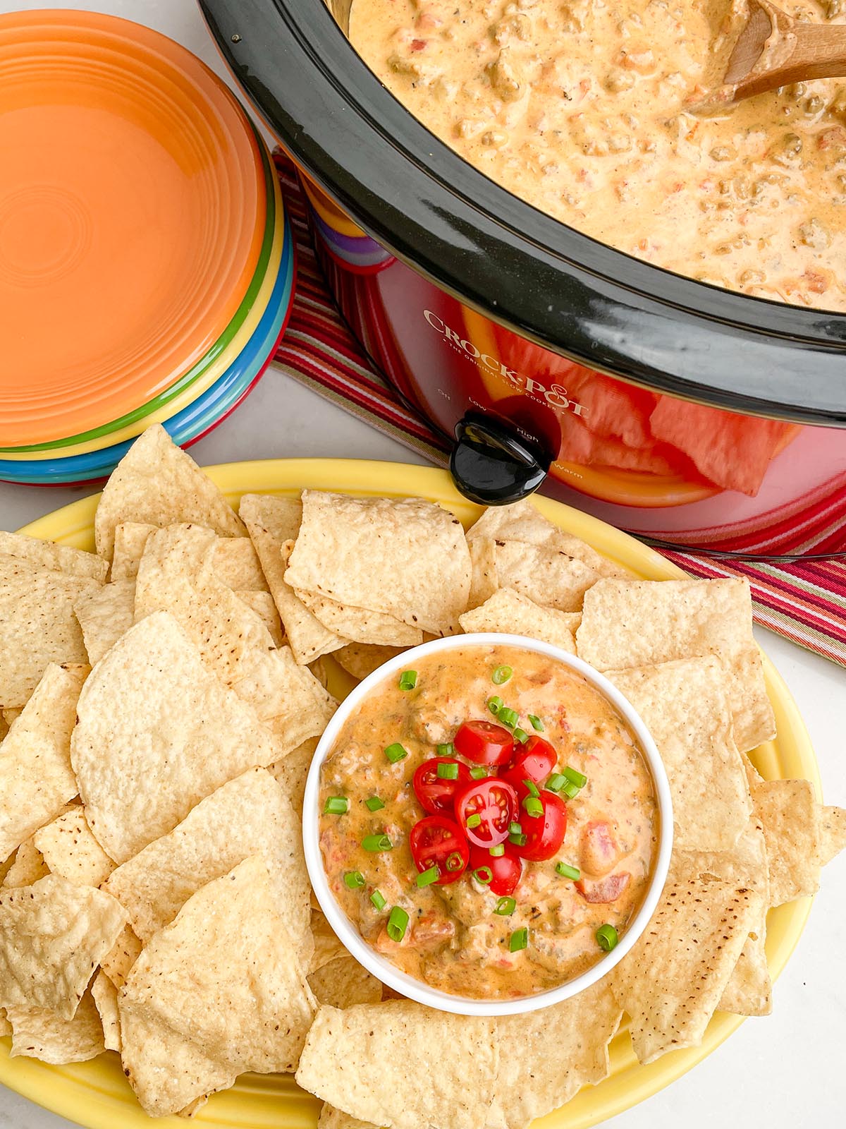Rotel dip with sausage in slow cooker and small bowl with platter of tortilla chips