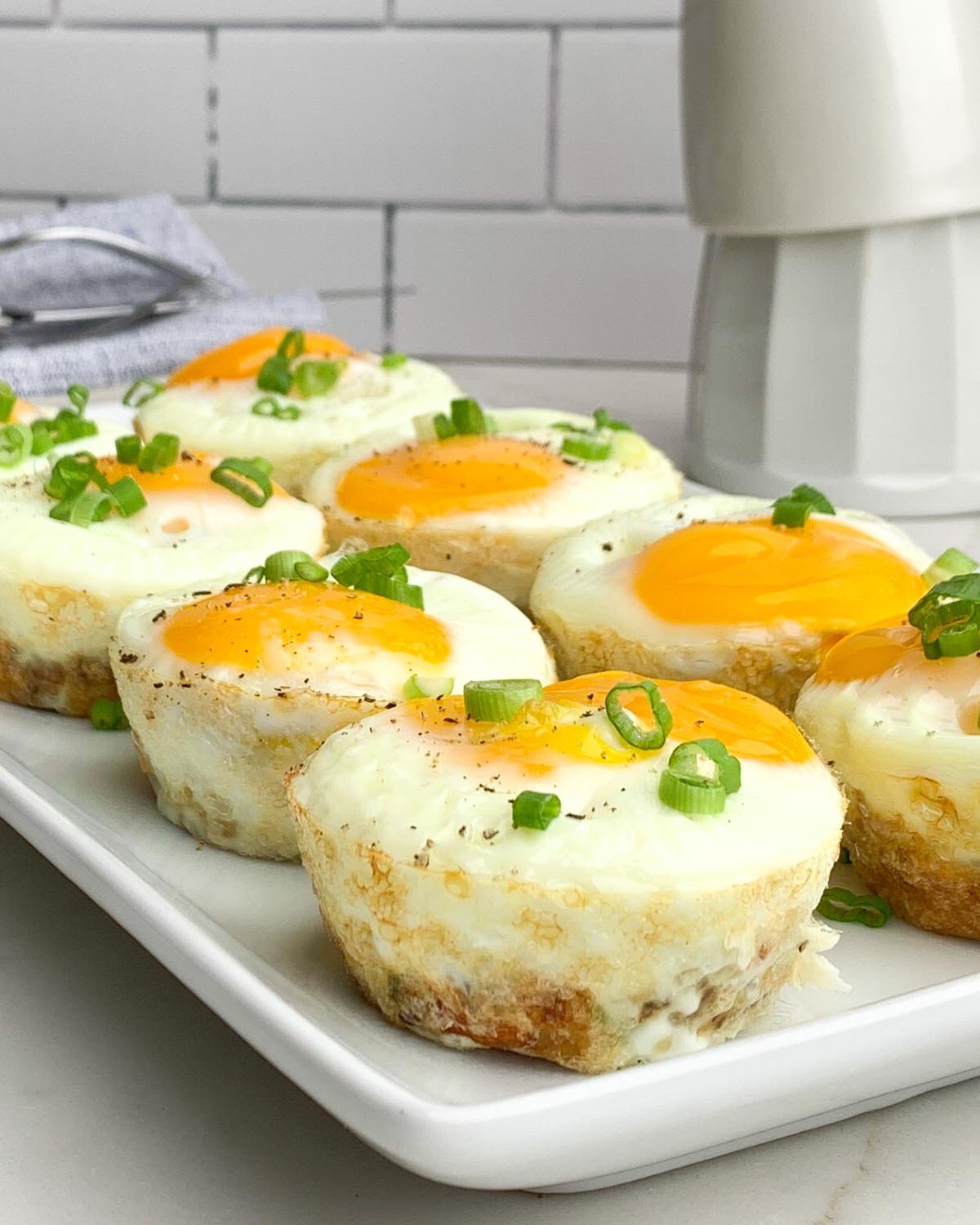 egg bites on a white plate topped with sliced green onions