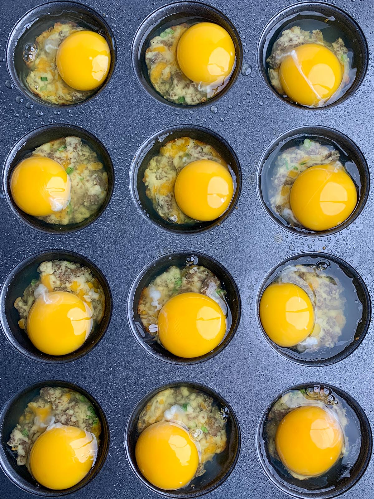 Raw egg over par baked biscuits in muffin cups