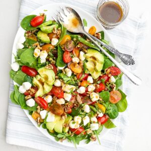 spinach and arugula salad on a white platter