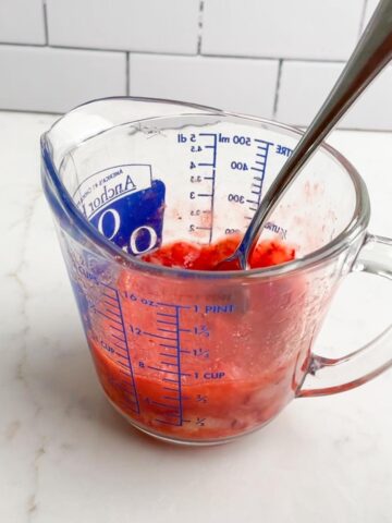 mashed strawberries in a glass measuring cup.