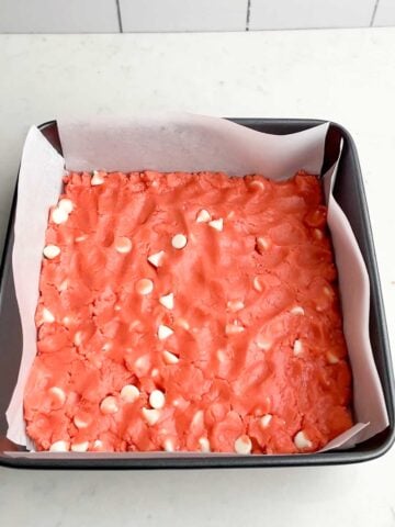 strawberry brownie batter pressed into a pan.