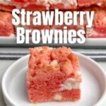 one Strawberry Brownie ona white plate in front of a platter of strawberry brownies