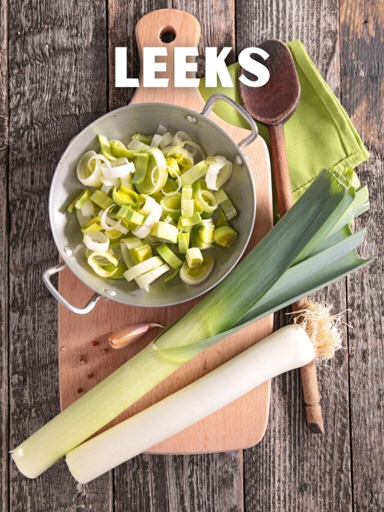 sliced leeks and full leeks on a cutting board