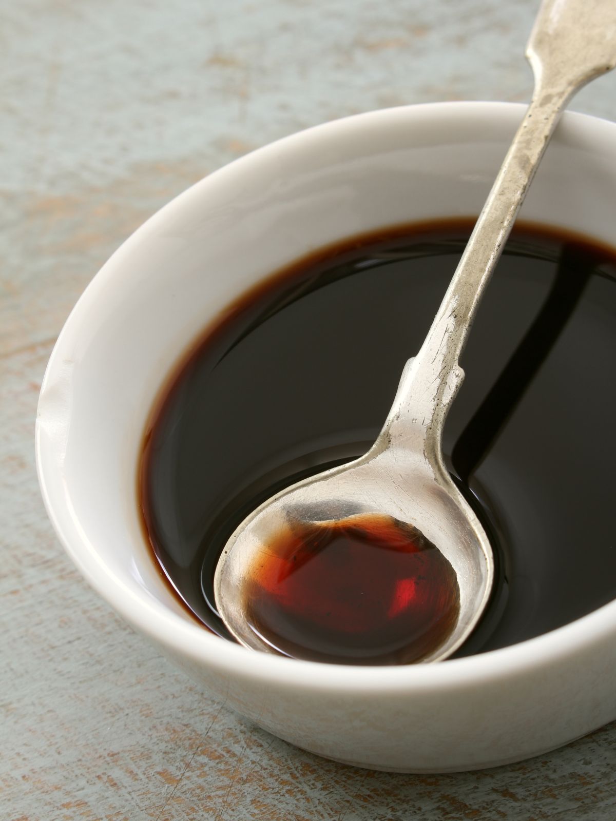 white bowl of balsamic vinegar with a spoon in it.