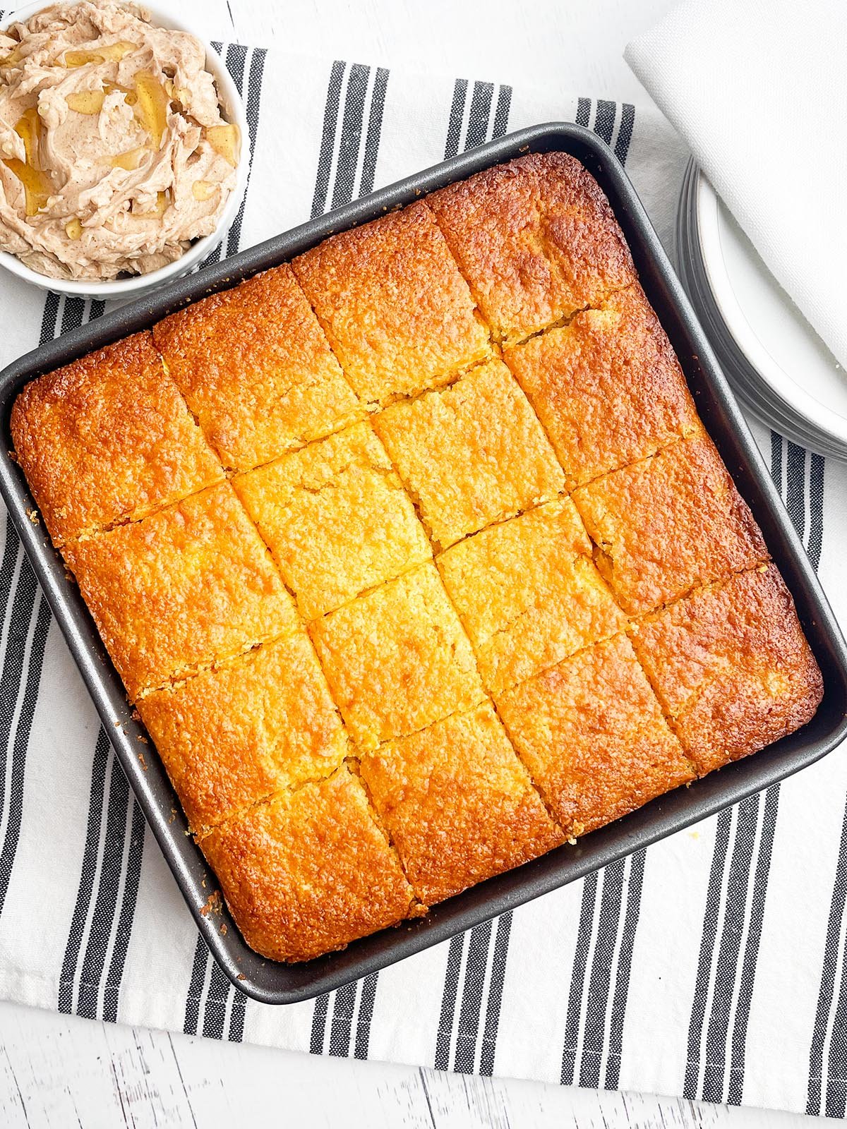 Jiffy sweet cornbread with creamed corn in square pan with cinnamon honey butter