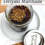 teriyaki marinade in a mason jar on a white plate and white napkin on a wooden cutting board