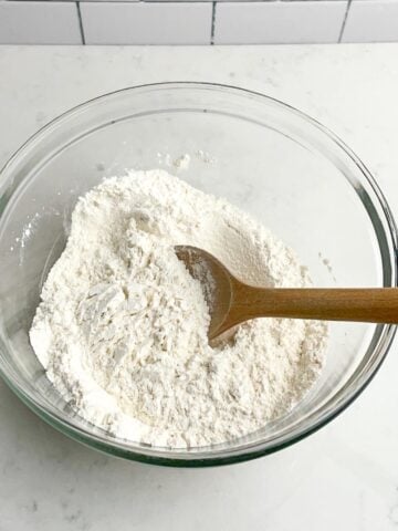 dry ingredients in a clear bowl with a wooden spoon.