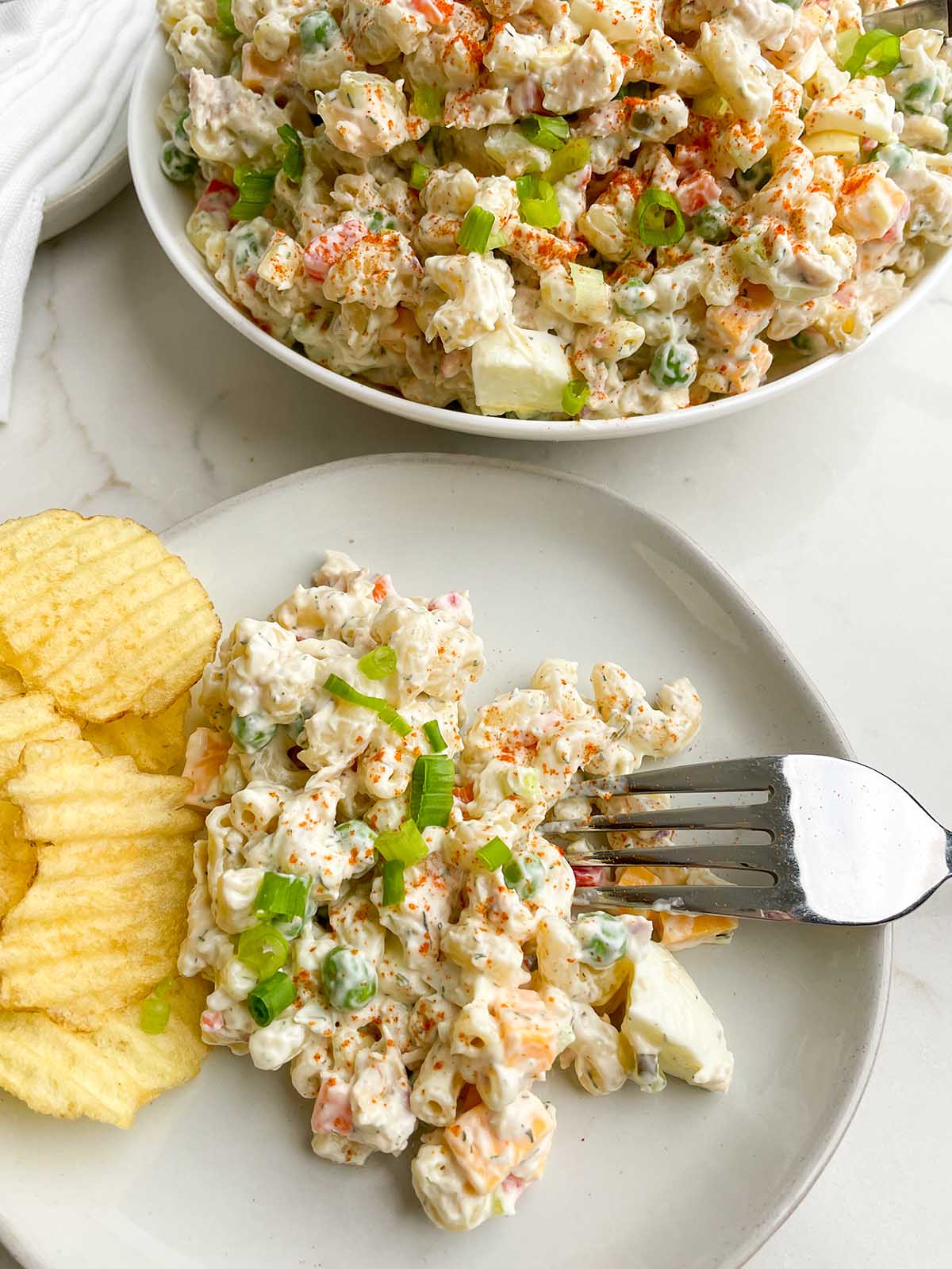 tuna macaroni salad on a white plate with potato chips