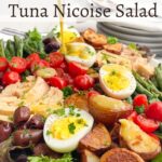 tuna nicoise salad on a platter with dressing being poured on top