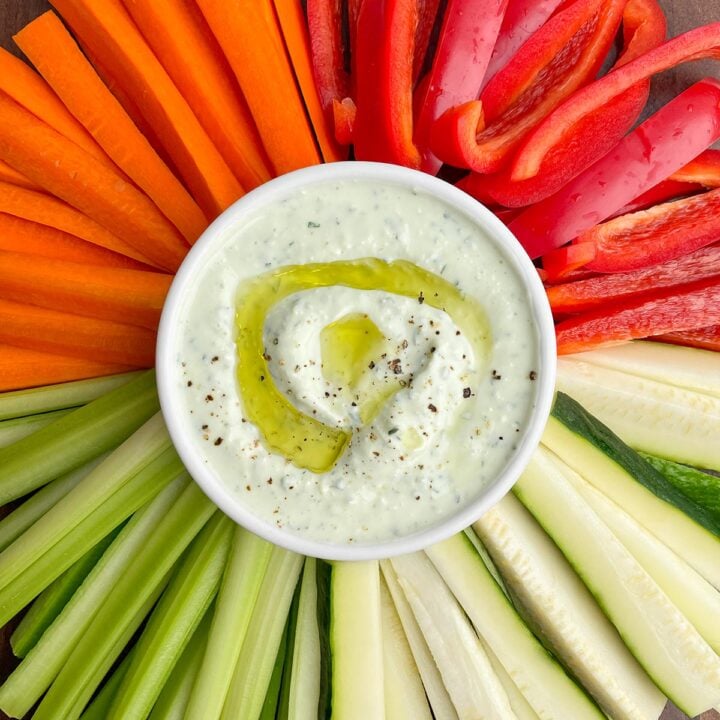 yogurt feta dip in a white bowl surrounded by vegetables